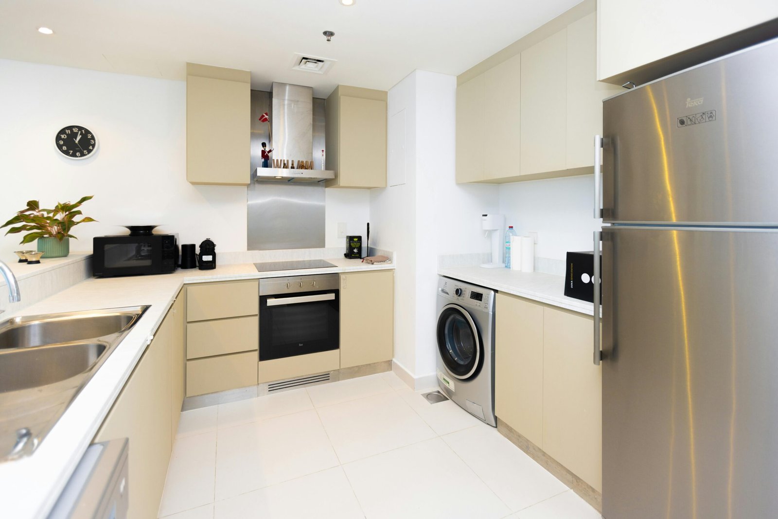 Contemporary kitchen featuring stainless steel appliances and beige cabinetry, ideal for apartment living.