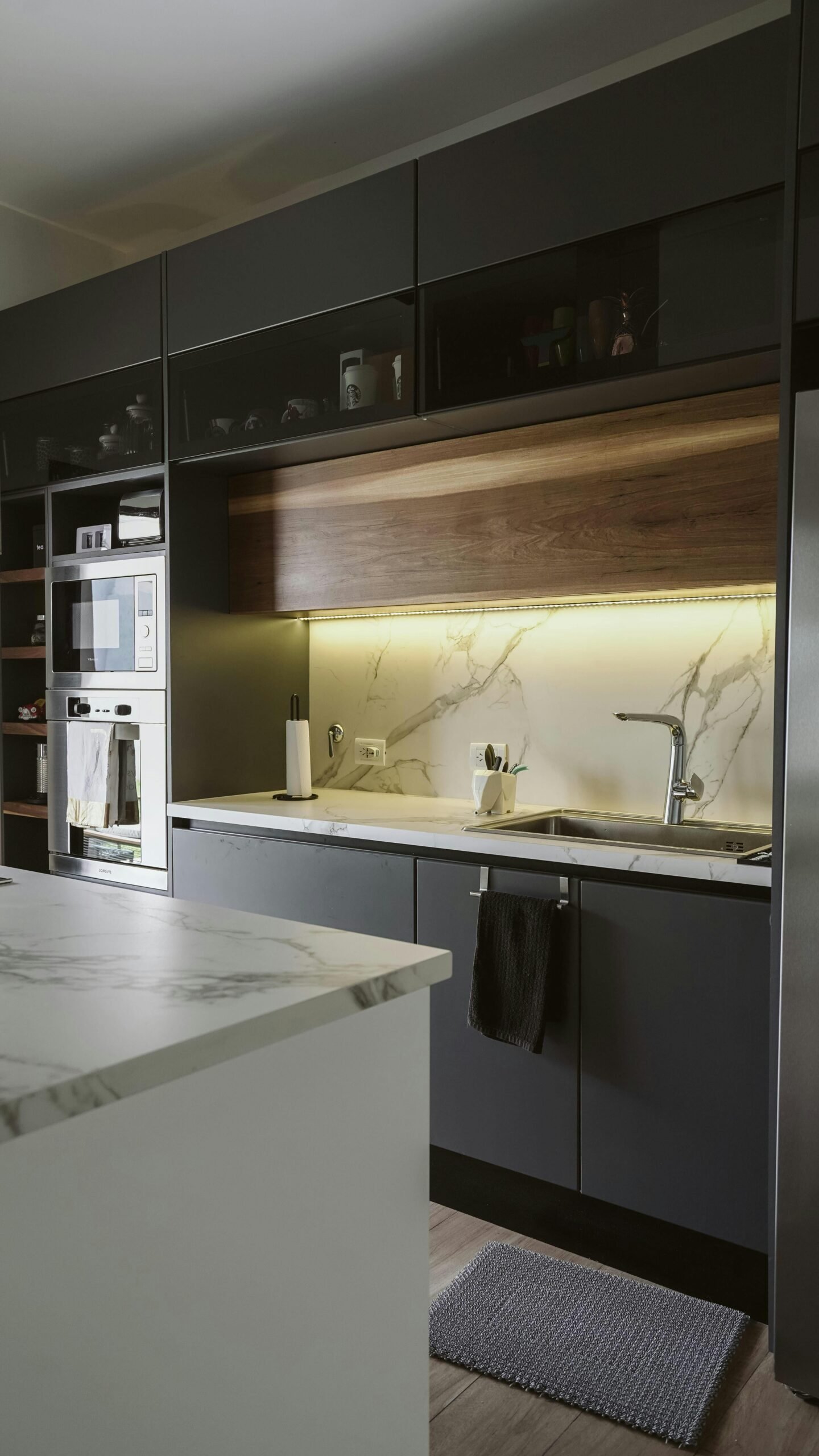 Sleek and modern kitchen featuring dark cabinetry and ambient lighting.